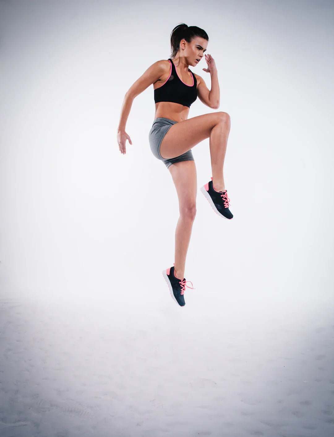 Athletic woman in workout clothes performing a high knee exercise for post-training nutrition and recovery.