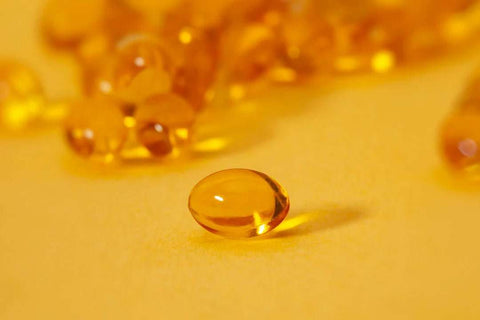 Close-up of yellow softgel supplement capsules representing risks of excessive supplementation.