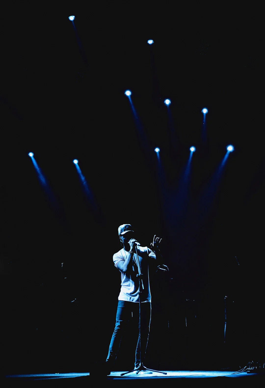 Singer performing on stage under blue spotlights with a dark background