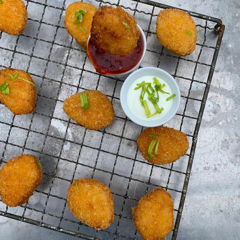 Crispy golden plant-based protein nuggets served on a wire rack with dipping sauces garnished with green herbs.