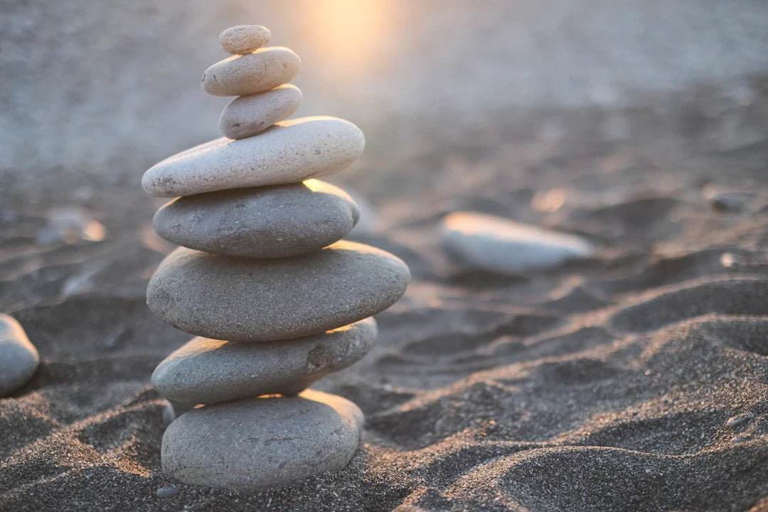 Balanced stack of smooth stones on sandy beach symbolizing balanced nutrition for athletes